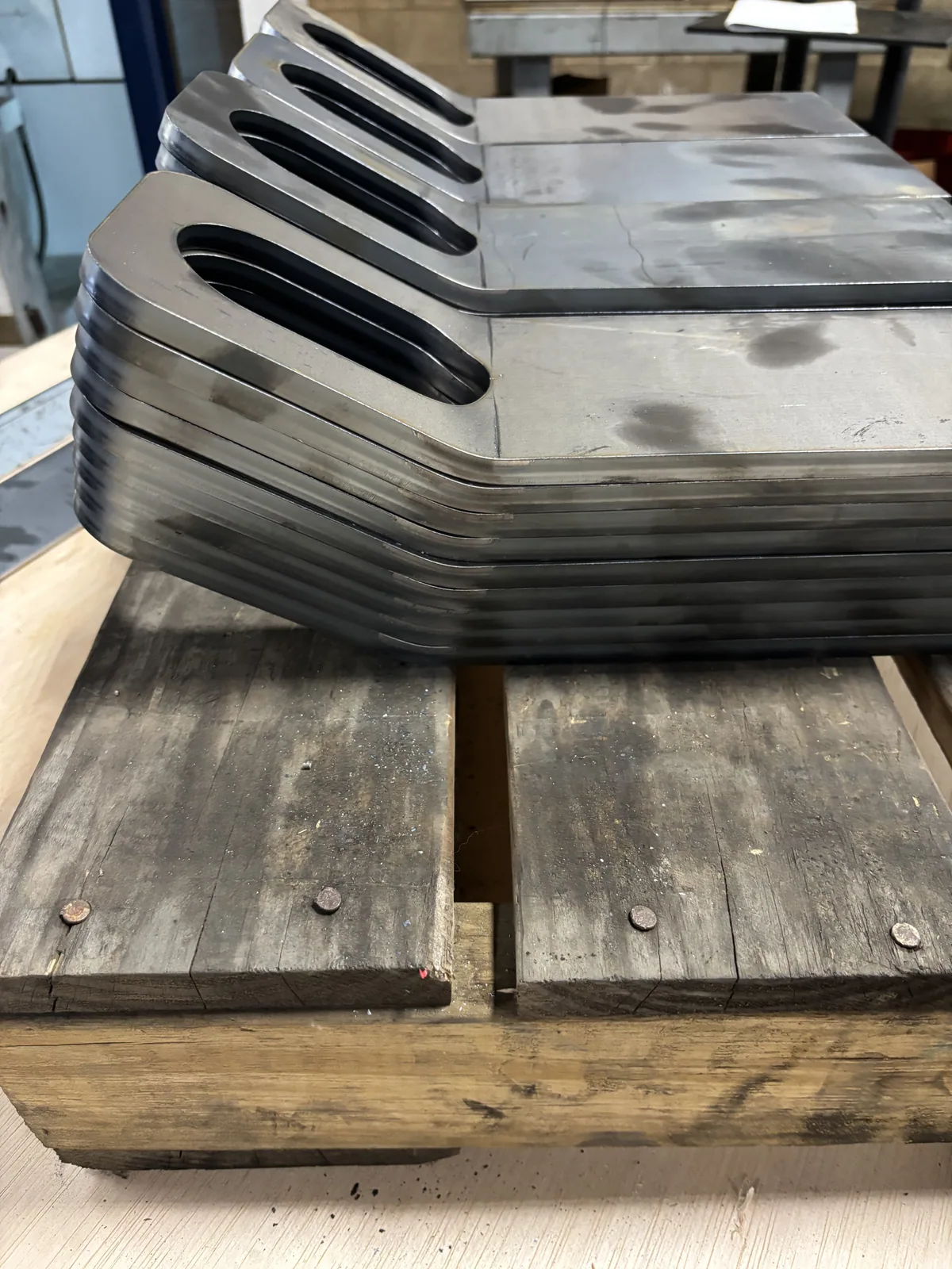 Matching formed metal brackets stacked on a pallet in the Ahner shop