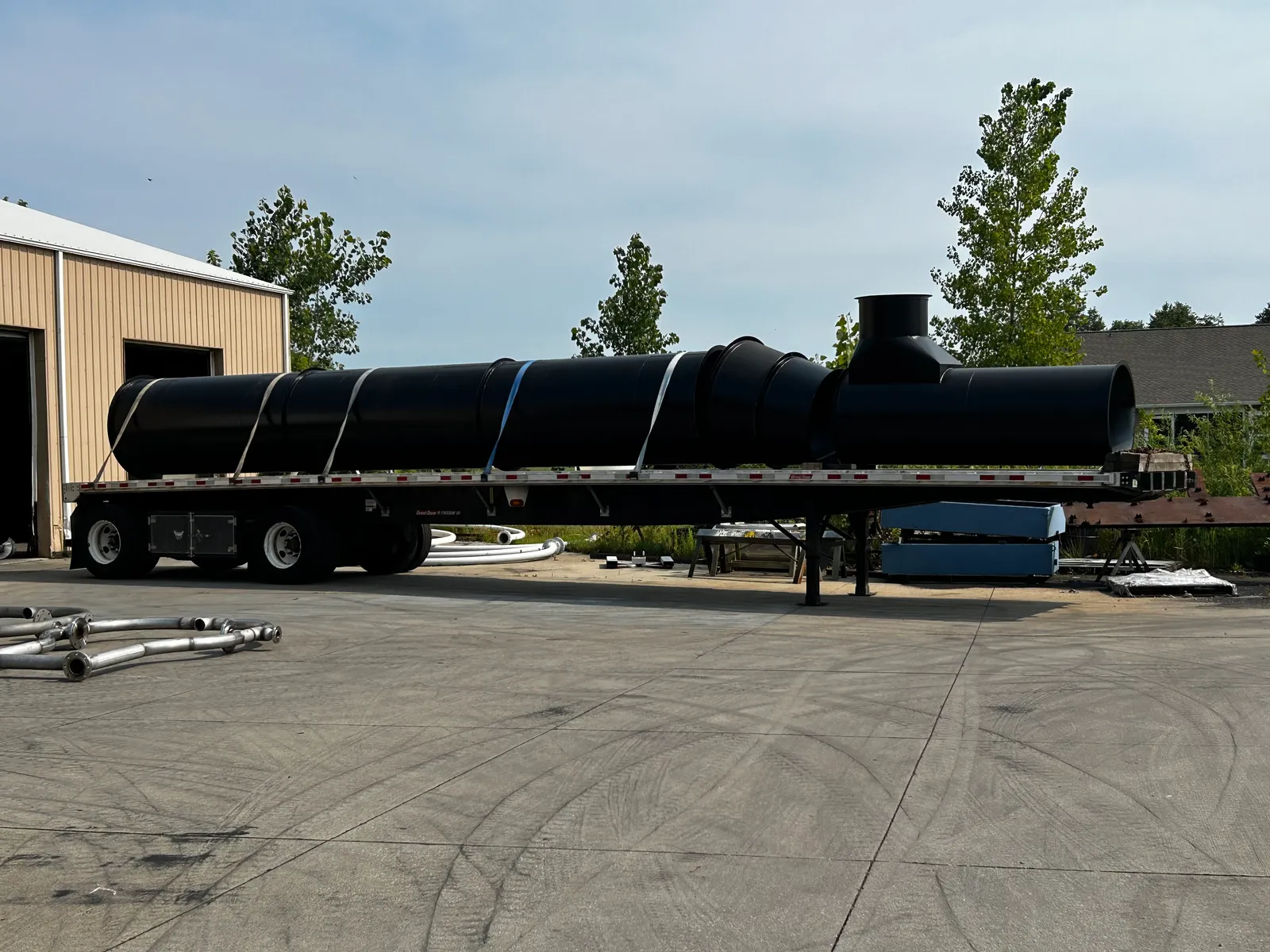 Large coated flanged duct sections secured on a flatbed outside Ahner Industrial